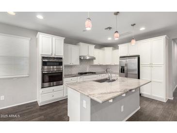 Bright kitchen features stainless steel appliances, granite countertops, white cabinets, and a center island with a sink at 10059 E Tamery Ave, Mesa, AZ 85212