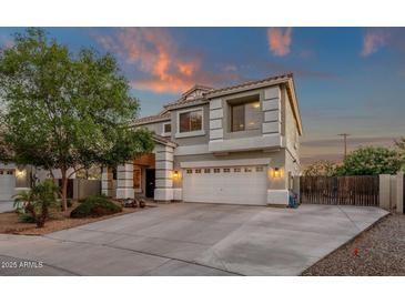 Charming two-story home with a well-manicured front yard at sunset at 14267 W Crocus Dr, Surprise, AZ 85379