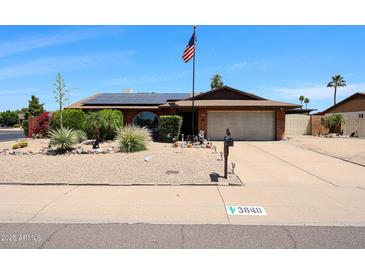 Charming single-story home featuring solar panels, desert landscaping, and a two-car garage at 3848 W Kings Ave, Phoenix, AZ 85053
