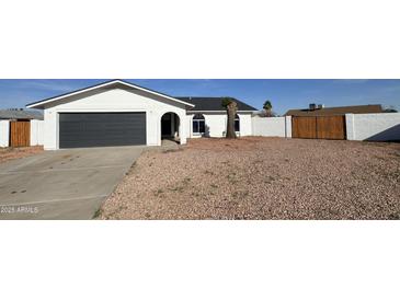 Charming single story home with a gray garage door, desert landscaping, and private fencing at 4125 W Villa Rita Dr, Glendale, AZ 85308