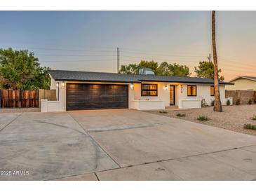 Contemporary home featuring a black garage door, modern lighting, and drought-resistant landscaping at 4910 E Shaw Butte Dr, Scottsdale, AZ 85254
