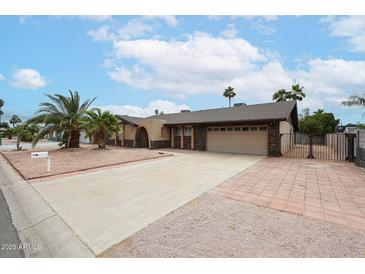 Charming single-story home with a two-car garage, desert landscaping, and a brick accent wall at 7439 E Ed Rice Ave, Mesa, AZ 85208