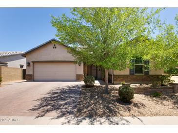 Charming single-story home featuring a lush shade tree, neutral color palette, and a brick-paved driveway at 8113 S 42Nd Dr, Laveen, AZ 85339