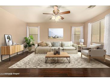 Staged living room with hardwood floors, ceiling fan, sofa, rug, side table, and decorations at 9207 W Kirby Ave, Tolleson, AZ 85353
