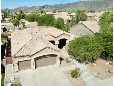 Aerial view of a home with a two-car garage, desert landscaping, and a beige tile roof nestled in a neighborhood at 16436 S 1St Ave, Phoenix, AZ 85045