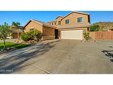 Two-story tan home with a two-car garage, desert landscaping, and a tile roof, perfect for curb appeal at 24645 N 65Th Ave, Glendale, AZ 85310