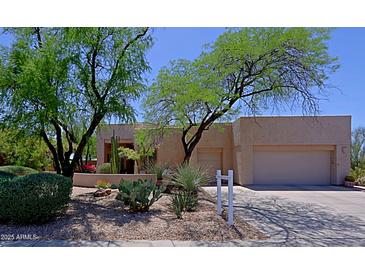 Southwestern home showcasing desert landscaping, mature trees, and a multi-car garage at 32516 N 68Th Pl, Scottsdale, AZ 85266
