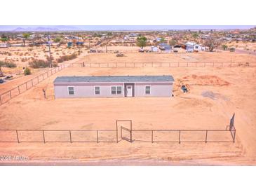 New single-story home with a gray roof and ample land, enclosed by a chain-link fence at 47654 W Venado Rd, Maricopa, AZ 85139