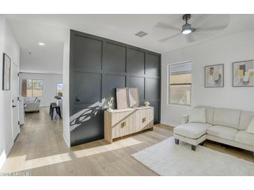 Stylish living room with a modern accent wall, ceiling fan and wood flooring at 8137 W Pueblo Ave, Phoenix, AZ 85043