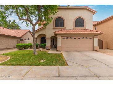 Inviting two-story home featuring a well-manicured lawn and a two-car garage with a red tile roof at 1231 W Mediterranean Dr, Gilbert, AZ 85233