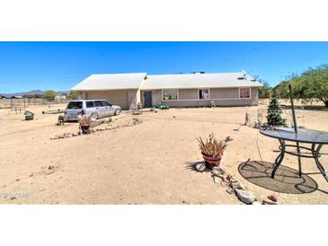 Single story home with a light colored roof and stucco walls, on a large dirt lot with car parked out front at 22222 W Lower Buckeye Rd, Buckeye, AZ 85326