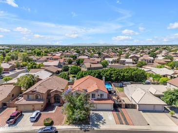 Expansive aerial view of a vibrant neighborhood with tidy homes, beautiful landscaping, and a stunning mountain backdrop at 8931 W Alex Ave, Peoria, AZ 85382