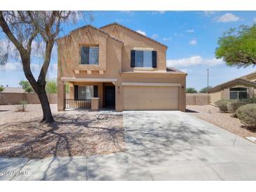 Two-story tan home featuring a two-car garage, a covered porch, and manicured landscaping at 23772 W Grove St, Buckeye, AZ 85326