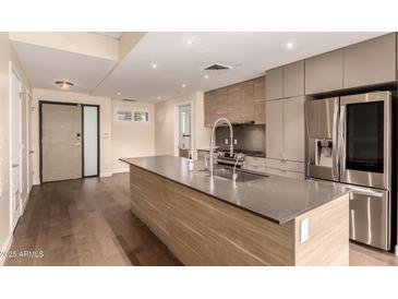 Modern kitchen features stainless steel appliances, light wood cabinets and a spacious center island with stone countertops at 2300 E Campbell Ave # 114, Phoenix, AZ 85016