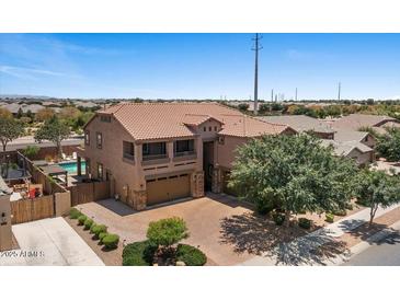 Two-story home with a brick driveway, three-car garage, and desert landscaping at 23081 S 223Rd Way, Queen Creek, AZ 85142