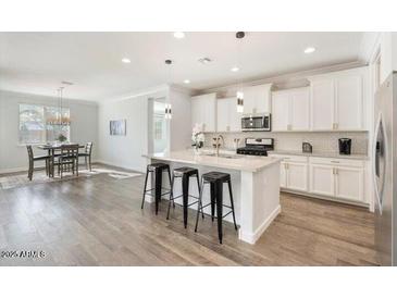 Open kitchen featuring an island with bar seating, stainless steel appliances and a dining area in a spacious layout at 4360 N 186Th Ln, Goodyear, AZ 85395
