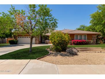 Beautiful single-story home with a well-manicured lawn, colorful flowering bushes, and a two car garage at 4404 W Olney Ave, Laveen, AZ 85339