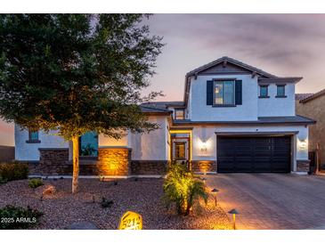 Elegant two-story home featuring a dark garage door, stucco siding, stone accents, and professional desert landscaping at 5212 S Seton Ct, Gilbert, AZ 85298