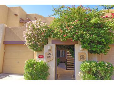 Charming condo entrance with vibrant flowering bushes, offering a welcoming and picturesque curb appeal at 7021 E Earll Dr # 204, Scottsdale, AZ 85251