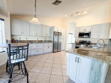 Spacious kitchen featuring stainless steel appliances, granite countertops, and tiled floors at 17371 N 86Th Ave, Peoria, AZ 85382