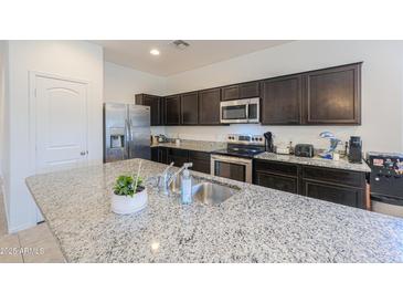This kitchen boasts stainless steel appliances, granite countertops, and dark cabinets, creating a modern and stylish space at 17851 N Mughetto Dr, Maricopa, AZ 85138