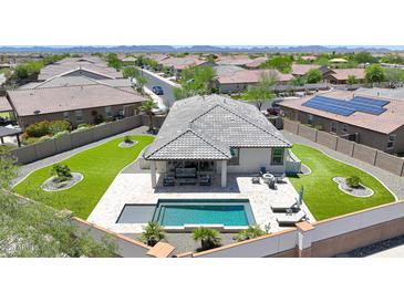 Aerial view of the home featuring a backyard oasis with a pool, spa, and covered patio, surrounded by lush landscaping at 18000 W Thistle Landing Dr, Goodyear, AZ 85338