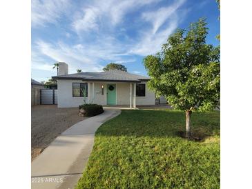 Charming exterior features a white brick facade, well-manicured lawn, and inviting turquoise front door at 2246 E Yale St, Phoenix, AZ 85006