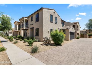 Charming stucco home with a balcony, well-maintained landscaping, and a brick driveway leading to an attached garage at 2363 W Dusty Wren Dr, Phoenix, AZ 85085