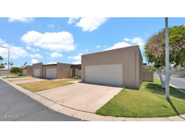 Street view of townhomes featuring attached garages, well-maintained lawns, and desert landscaping at 3345 E University Dr # 47, Mesa, AZ 85213