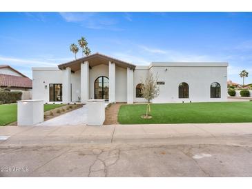 An inviting, modern, single-story home featuring a crisp white stucco exterior and an arched entryway at 9820 N 87Th Pl, Scottsdale, AZ 85258