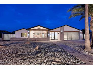 Beautiful modern home with desert landscaping, unique architectural details, and a sleek glass garage door at 11007 N 26Th St, Phoenix, AZ 85028