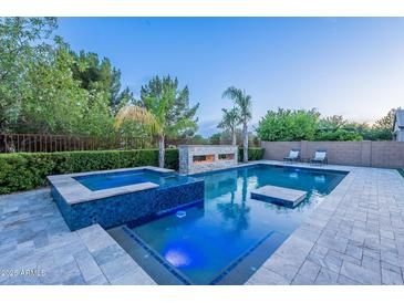 Inviting pool with integrated spa, in-pool seating, and stone fireplace feature at 22255 E Quintero Rd, Queen Creek, AZ 85142