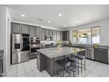 Contemporary kitchen featuring gray cabinets, stainless steel appliances, and a large island with bar seating at 22341 N 100Th Ln, Peoria, AZ 85383
