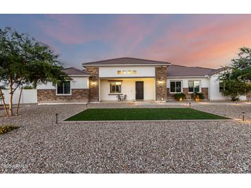 Charming single-story home featuring a decorative stone facade and tidy lawn with mature landscaping at 3911 N 197Th Ave, Buckeye, AZ 85396