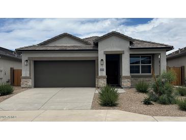 Charming single-story home features a two-car garage, desert landscaping, and modern architectural details at 40070 W Venture Rd, Maricopa, AZ 85138