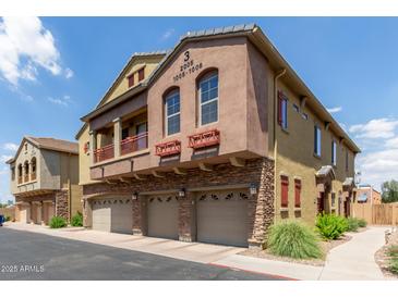 A three-story townhome boasts a stucco exterior, multi-car garages, and eye-catching stone accents at 1350 S Greenfield Rd # 1005, Mesa, AZ 85206