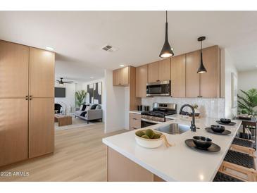 Modern kitchen featuring light wood cabinets, stainless appliances, quartz countertops and an island at 1720 W Behrend Dr, Phoenix, AZ 85027
