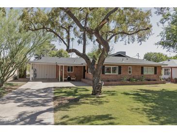 Charming brick home with mature tree, covered carport and inviting front porch at 1839 E Palo Verde Dr, Phoenix, AZ 85016