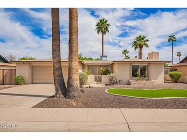 Charming single-story home boasting a well-maintained yard with lush landscaping and palm trees at 1887 E La Donna Dr, Tempe, AZ 85283
