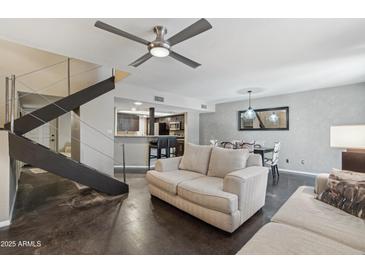 Open-concept living area with modern stairs, ceiling fan, and view into kitchen and dining space at 3030 N Hayden Rd # 28, Scottsdale, AZ 85251