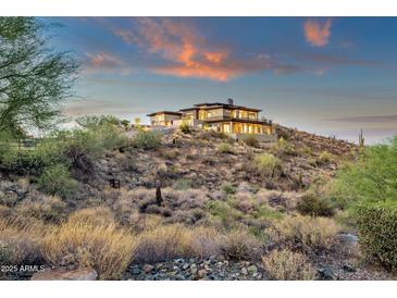 Expansive custom home on a hillside featuring multiple patios, stone accents, and breathtaking views during sunset at 16119 N Desert Fox Pkwy, Fountain Hills, AZ 85268