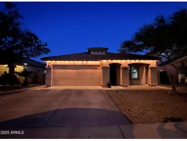 Charming single-story home featuring a two-car garage and nicely landscaped front yard at night at 24229 W Tonto St, Buckeye, AZ 85326