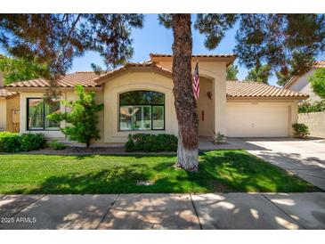 Charming single-story home with a well-manicured lawn, two-car garage, and a welcoming arched entryway at 9575 S Ash Ave, Tempe, AZ 85284