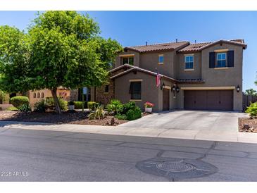 Two-story stucco home featuring a three-car garage, mature landscaping, and a tiled roof at 19427 W Colter St, Litchfield Park, AZ 85340