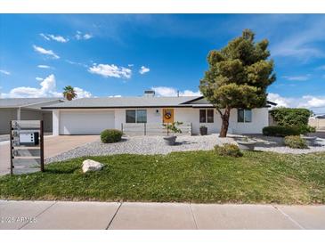 Charming single-story home with a manicured lawn and inviting curb appeal under a bright blue sky at 3850 E Ludlow Dr, Phoenix, AZ 85032