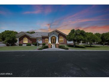 Charming red brick home with arched entryway and manicured lawn at twilight at 4040 E Mclellan Rd # 16, Mesa, AZ 85205