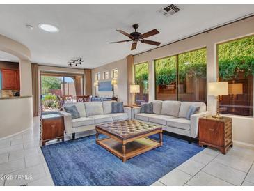 Spacious living room with large windows, plush sofas, and direct access to outdoor patio at 41318 N Belfair Way, Anthem, AZ 85086