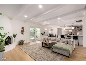 Bright, open-concept living room with wood floors, fireplace, kitchen and access to a backyard pool at 6835 E Friess Dr, Scottsdale, AZ 85254