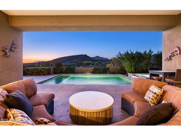 Inviting covered patio with plush seating overlooking a sparkling pool and captivating mountain views at 9894 E Miramonte Dr, Scottsdale, AZ 85262