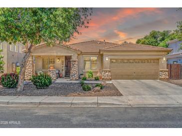 Charming single-story home with stone accents, a well-manicured yard, and a spacious two-car garage at 3214 N 138Th Dr, Avondale, AZ 85392
